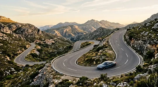 Vue aérienne d'une route de montagne sinueuse avec une voiture électrique en descente, mettant en évidence le système de freinage régénératif